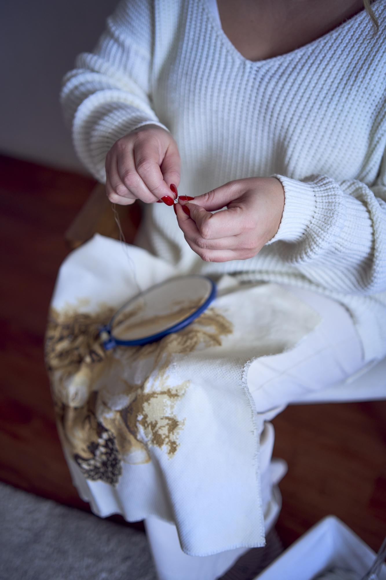 close-up of hands embroidering a floral motif